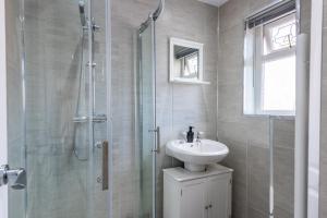 a bathroom with a sink and a glass shower at Bright 3br Home In Central Belfast in Belfast