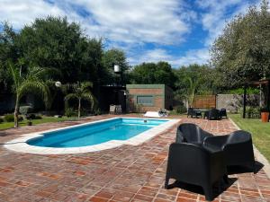 a swimming pool with black chairs and a brick patio at Las Catalinas cabañas in San Fernando del Valle de Catamarca +10 photos