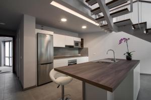a kitchen with a wooden table and a stainless steel refrigerator at Apartamentos Cordial Mogán Paraíso in Puerto de Mogán