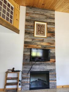 Cette chambre dispose d'un mur en bois, d'une télévision et d'une cheminée. dans l'établissement Chalet au lac Saint-Jean, à Dolbeau-Mistassini