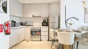 a kitchen with white cabinets and a table and a refrigerator at 1BR -Marina Solene Yas Island 10 Min to Grand Prix in Abu Dhabi