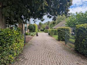 a brick driveway leading to a house with a fence at Appartement Het Gewei in Rotsterhaule
