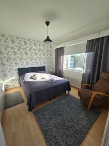 Un dormitorio con una cama y una silla y una ventana. en Apartment Sotilastorpantie, en Kokkola