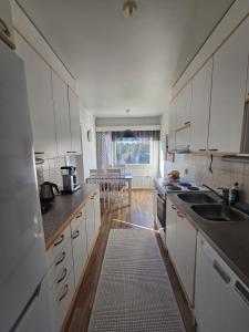 cocina con armarios blancos y alfombra de cocina en Apartment Sotilastorpantie, en Kokkola