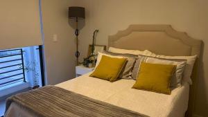 a bedroom with a bed with two yellow pillows at Cosy Flat Steps from the Beach in Cape Town