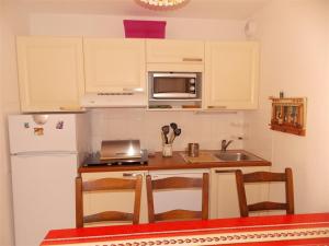 une cuisine avec des armoires blanches, un évier et un réfrigérateur dans l'établissement Appartement T2 Cabine avec Jardin près de Luchon - Pour 6 Pers, Animaux Admis, Parking sécurisé - FR-1-313-142, à Montauban-de-Luchon 5 autres photos