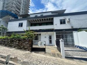 a white house with a gate in front of it at Quarto a 150m da Praia do Farol da Barra III in Salvador