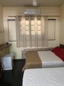 a bedroom with two beds and a window with curtains at Falcon Hotel in Bauru +13 photos