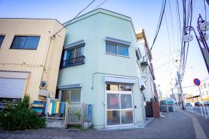 ein weißes Gebäude mit einer Tür auf einer Straße in der Unterkunft Voyager Inn in Tokio