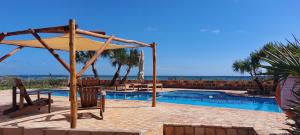 a swimming pool with a umbrella and chairs and the ocean at Bay View Lodge in Miramar