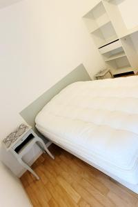 a white bed in a small room with a table at Appartement calme avec balcon in Pouzauges