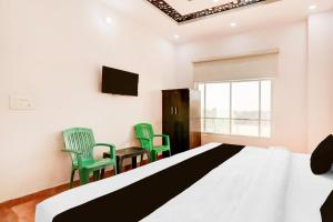 a bedroom with a large bed and two green chairs at Hotel O The urban inn hotel and banquet in Kākori