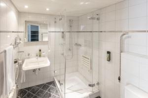 une salle de bain blanche avec une douche et un lavabo dans l'établissement Hotel und Restaurant zum goldenen Kopf, à Bülach