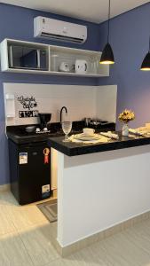 a kitchen with a counter with a stove and a microwave at Pousada Vila Caetité Lofts in Caetité