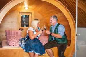 Ein Mann und eine Frau sitzen auf einem Bett und trinken Wein. in der Unterkunft Weinfass Chalet Für 4 In Grub An Der March in Grub an der March + 7 Fotos
