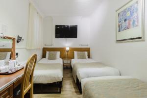 Una habitación de hotel con tres camas y un escritorio. en The Chapter Hotels - Falcon Hotel, en Londres 64 fotos más