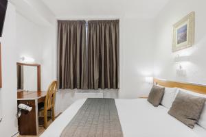 Una habitación de hotel con una cama, un escritorio y una ventana. en The Chapter Hotels - Falcon Hotel, en Londres