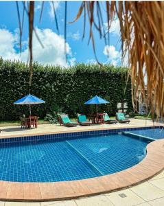 une piscine avec chaises longues et parasols dans l'établissement Pousada Villa Morena, à Porto de Pedras