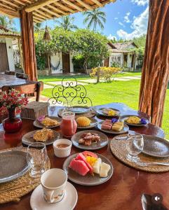 une table avec des assiettes de nourriture dessus dans l'établissement Pousada Villa Morena, à Porto de Pedras