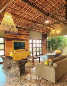 - un salon avec une télévision, un canapé et des chaises dans l'établissement Pousada Villa Morena, à Porto de Pedras