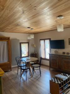 a living room with a wooden ceiling and a table and chairs at Chez Philomène in Saint-Martin-Vésubie