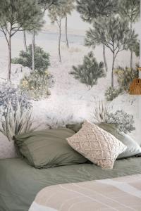 a bed with two pillows and a wall with trees at Duplex Cocon & Vue Mer Imprenable in Arcachon