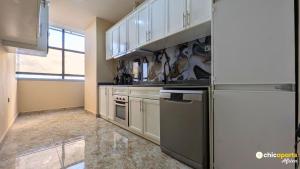 a kitchen with white cabinets and stainless steel appliances at Chic studio with parking and rooftop in Yaoundé