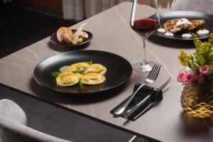 a table with plates of food and a glass of wine at NH Milano Machiavelli in Milan
