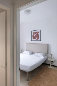 a bedroom with a bed with white sheets and a mirror at Vivace Bilocale con vista sul Naviglio -Mirable PM in Milan