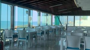a dining room with tables and chairs and windows at Abaş Masmavi Otel in Yumurtalık