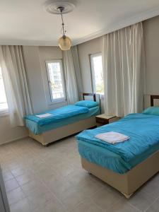 a bedroom with two beds and two windows at Abaş Masmavi Otel in Yumurtalık