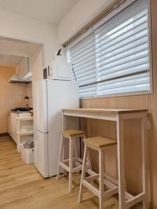 a kitchen with a refrigerator and a table and stools at Tokyo Shinjuku Mia in Tokyo