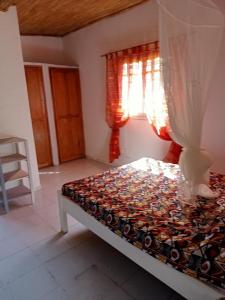 a bedroom with a bed and a window with curtains at Chambre d'hôte Maryvonne & Mamadou in Nianing