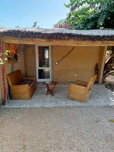 a patio with two chairs and a table on a house at Chambre d'hôte Maryvonne & Mamadou in Nianing