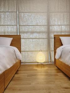 a bedroom with two beds and a lamp on the floor at Tokyo Shinjuku Mia in Tokyo