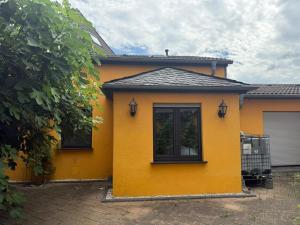 a yellow house with two windows and a garage at Bungalow sunshine in Weilerswist