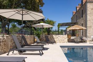 een groep stoelen en parasols naast een zwembad bij Le Domaine de la Haye Chambres d'Hôtes in Saint-Christophe-du-Bois