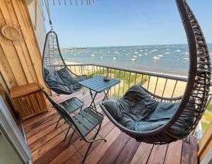 a porch with two chairs and a table on a balcony at Duplex Cocon & Vue Mer Imprenable in Arcachon