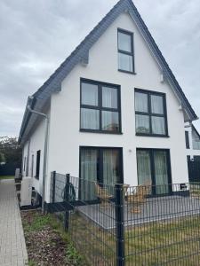 a white house with black windows and a fence at Moderne Doppelhaushälften - Rose Garden 1 & 2 - 17 km vom Frankfurter Flughafen und 30 km vom Messegelände entfernt in Offenbach