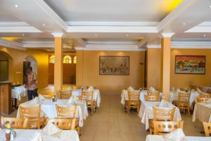 ein Esszimmer mit weißen Tischen und Stühlen in der Unterkunft Hotel Chez Lando in Kigali