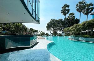 una piscina con agua azul y palmeras en Arom Wongamart by David Home, en Norte de Pattaya
