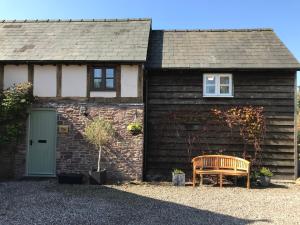 a house with a bench in front of it at The Granary, Wonderful Riverside Accommodation in Bodenham