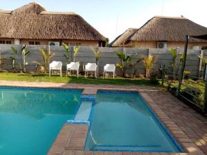 a villa with a swimming pool in front of a house at Modipane Guest Lodge in Tlokweng