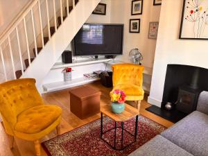 a living room with two chairs and a tv at Elegant Riverside Cottage With Free Parking in Canterbury