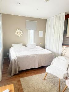 Un dormitorio con una cama blanca y una silla. en Ihana Helmi - The Nest for Two, en Vaasa 5 fotos más