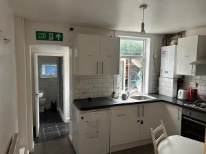 a kitchen with white cabinets and a sink at Arden Home in Gillingham