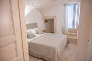 a bedroom with a white bed and a window at Pregio Villas per Suite Oronzo Charme&Pool in Ostuni