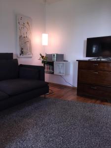 uma sala de estar com um sofá preto e uma televisão em Garten86 em Bremen