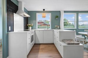 a kitchen with white cabinets and a table and chairs at 40575-Juelsminde-Pot-Strandby-100 in Sønderby