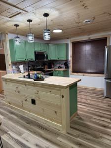 a kitchen with green cabinets and a kitchen island at The Brady Retreat Hot tub and pool in McArthur
